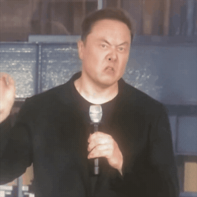 A Man In A Black Suit Is Holding A Microphone And Making A Funny Face GIF