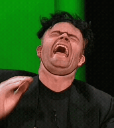 A Man In A Black Suit Is Making A Funny Face GIF