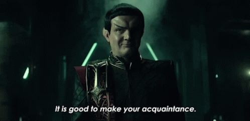 A Man In A Black Suit Is Standing In A Dark Room . GIF