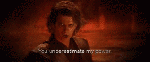 A Man In A Black Suit Is Standing In A Dark Room With A Red Background . GIF