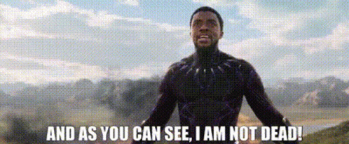 A Man In A Black Suit Is Standing In A Field And Saying `` And As You Can See , I Am Not Dead '' GIF