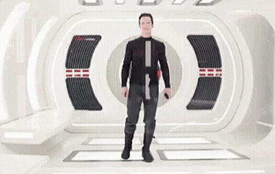 A Man In A Black Suit Is Standing In A Futuristic Room Holding A Gun . GIF