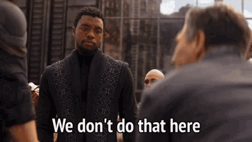 A Man In A Black Suit Is Standing In Front Of A Group Of Men And Saying We Don 'T Do That Here . GIF