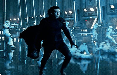 A Man In A Black Suit Is Standing In Front Of A Group Of Stormtroopers GIF