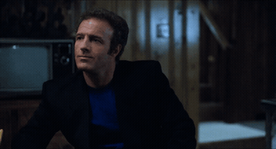 A Man In A Black Suit Is Talking To Another Man In A Blue Shirt GIF