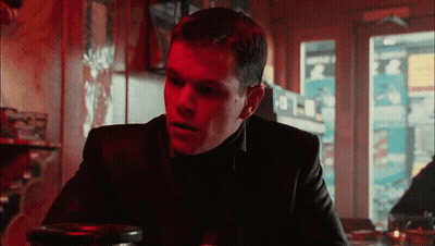 A Man In A Black Suit Sits At A Table In A Restaurant GIF