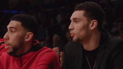 A Man In A Black Suit Sits Next To A Man In A Red Shirt GIF