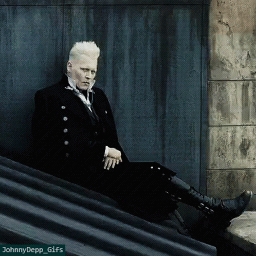 A Man In A Black Suit Sits On A Ledge With A Watermark That Says Johnny Depp Gifs GIF