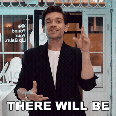 A Man In A Black Suit Stands In Front Of A Sign That Says " There Will Be " GIF