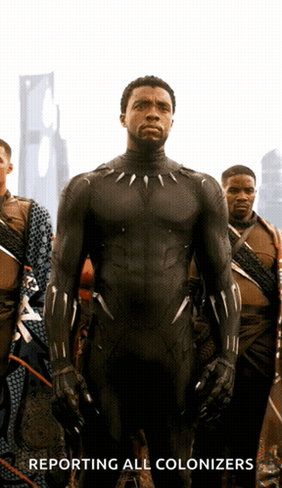 A Man In A Black Suit With The Words Reporting All Colonizers Behind Him GIF
