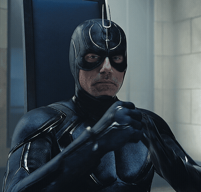 A Man In A Black Superhero Costume Is Holding A Bat GIF