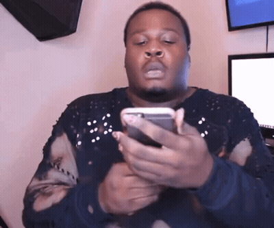 A Man In A Black Sweater Is Holding A Cell Phone GIF