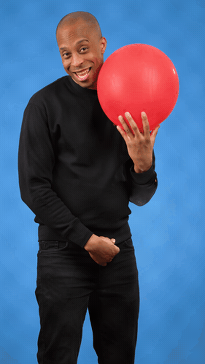 A Man In A Black Sweater Is Holding A Red Balloon In Front Of His Face GIF