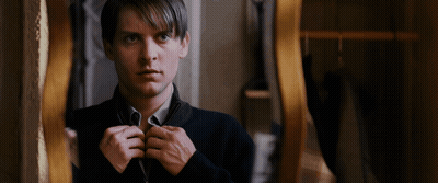 A Man In A Black Sweater Is Looking At Himself In A Mirror GIF