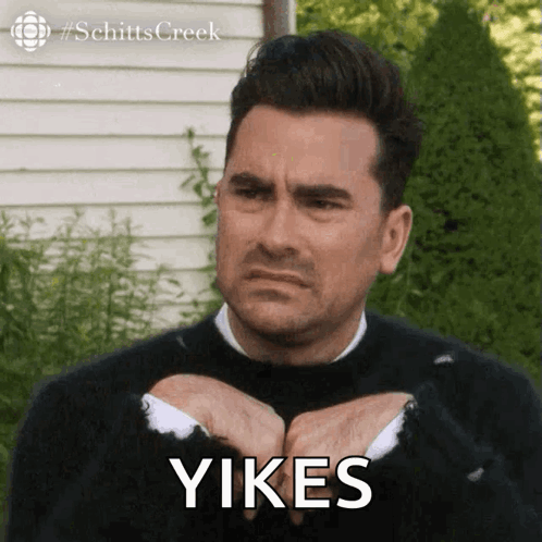 A Man In A Black Sweater Is Making A Face And The Word Yikes Is On His Face GIF