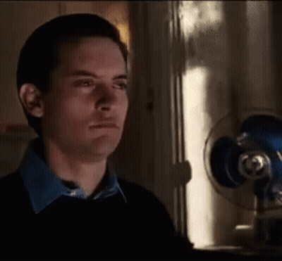 A Man In A Black Sweater Is Standing In Front Of A Fan . GIF