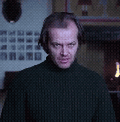 A Man In A Black Sweater Is Standing In Front Of A Fireplace And Making A Funny Face . GIF