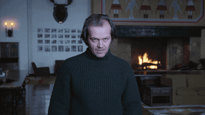 A Man In A Black Sweater Is Standing In Front Of A Fireplace GIF