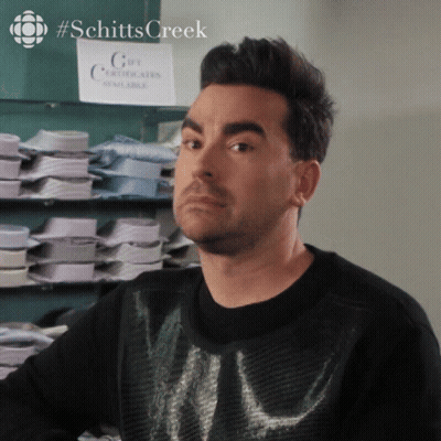 A Man In A Black Sweater Stands In Front Of A Sign That Says Gift Certificates Available GIF
