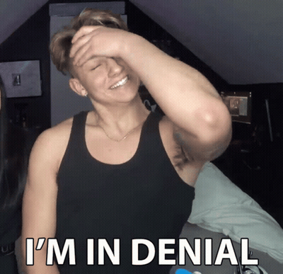 A Man In A Black Tank Top Covering His Face With His Hand And The Words I 'M In Denial Below Him GIF