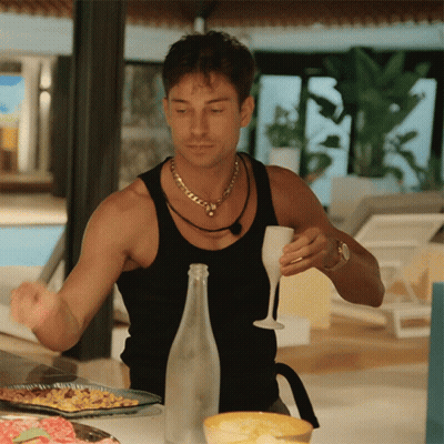 A Man In A Black Tank Top Holds A Wine Glass GIF