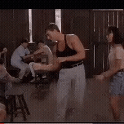 A Man In A Black Tank Top Is Dancing In Front Of A Crowd GIF