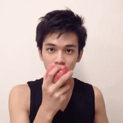 A Man In A Black Tank Top Is Eating A Red Apple . GIF
