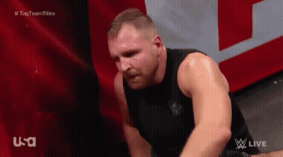 A Man In A Black Tank Top Is Sitting On The Floor With His Head Down . GIF