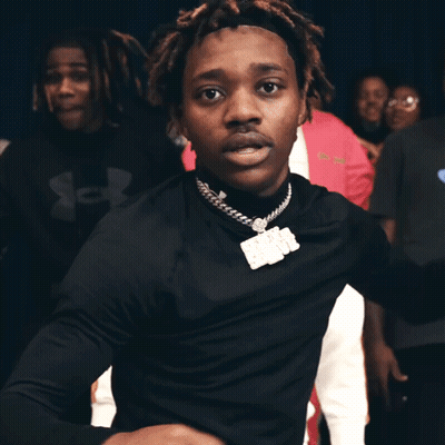 A Man In A Black Turtleneck Is Dancing In Front Of A Crowd Of People GIF