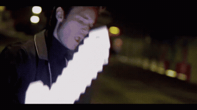 A Man In A Black Turtleneck Is Holding A White Light GIF
