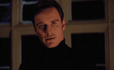 A Man In A Black Turtleneck Stands In Front Of A Window With Perfection Written On The Bottom Right GIF