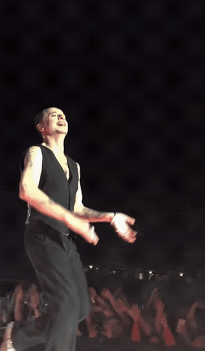 A Man In A Black Vest Is Dancing On A Stage GIF