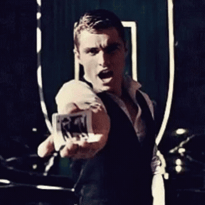 A Man In A Black Vest Is Holding A Piece Of Paper In His Hand GIF