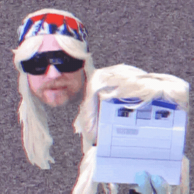A Man In A Blonde Wig And Sunglasses Holds A Printer GIF