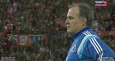 A Man In A Blue Adidas Shirt Stands In Front Of A Sign That Says Soft GIF