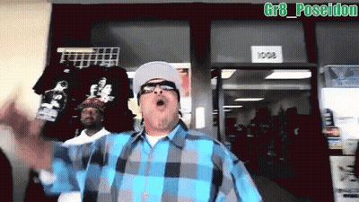 A Man In A Blue And Gray Plaid Shirt Stands In Front Of A Store With A Sign That Says 1008 GIF