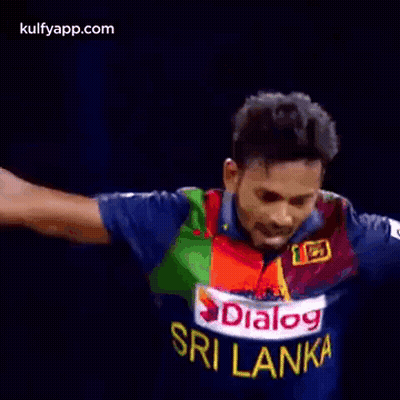 A Man In A Blue And Green Jersey Is Standing In Front Of A Referee . GIF