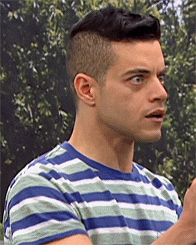 A Man In A Blue And Green Striped Shirt Looks To The Side GIF