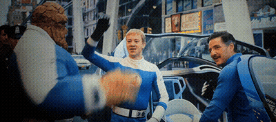 A Man In A Blue And White Costume Stands In Front Of A Sign That Says King Chester On It GIF