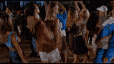 A Man In A Blue And White Jacket Is Dancing In A Crowd Of People . GIF