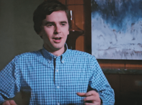 A Man In A Blue And White Plaid Shirt Is Holding A Glass Of Wine GIF