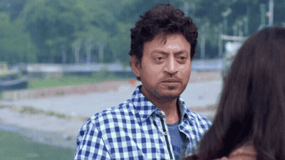 A Man In A Blue And White Plaid Shirt Is Looking At A Woman GIF