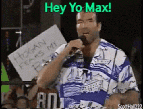 A Man In A Blue And White Shirt Is Holding A Microphone And A Sign That Says Hey Yo Max GIF