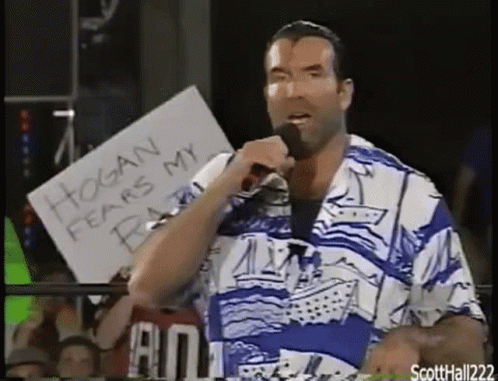 A Man In A Blue And White Shirt Is Holding A Microphone And A Sign That Says Hogan Fears My Beard . GIF