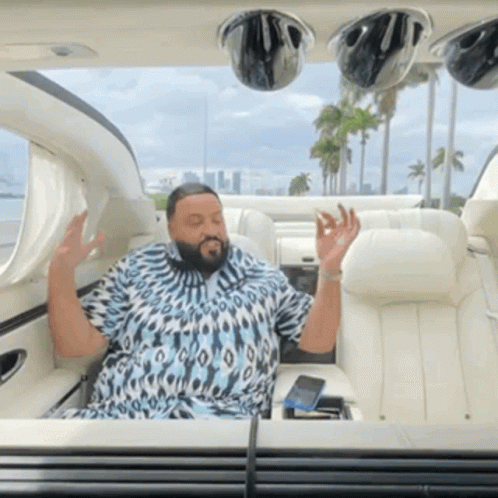 A Man In A Blue And White Shirt Is Sitting In A Car GIF