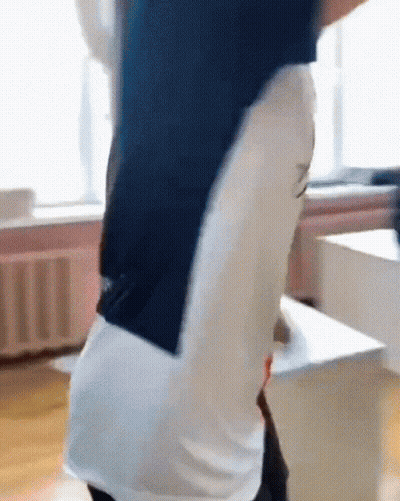 A Man In A Blue And White Shirt Is Standing In A Room With His Arms Outstretched . GIF