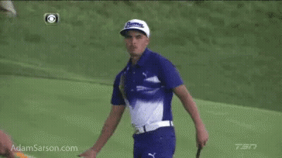 A Man In A Blue And White Shirt Is Standing On A Golf Course GIF
