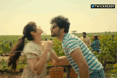 A Man In A Blue And White Striped Shirt Is Carrying A Woman On His Shoulders GIF