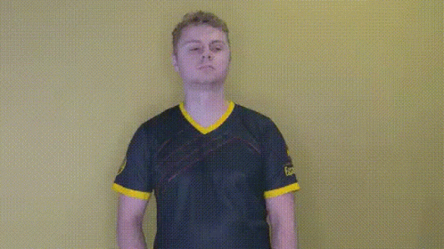 A Man In A Blue And Yellow Shirt Is Standing In Front Of A Yellow Background . GIF