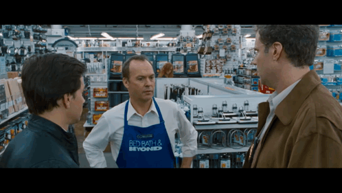 A Man In A Blue Apron That Says Bed Bath & Beyond GIF